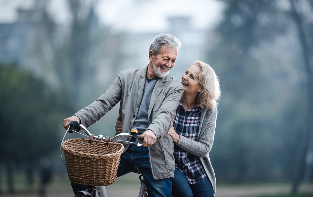 Happy senior couple talking while cycling in nature.